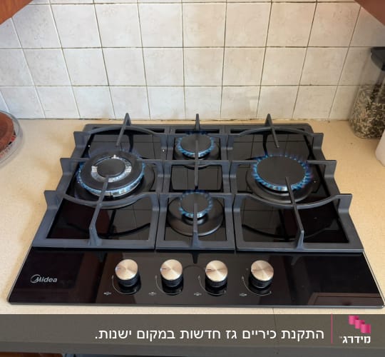 כיריים גז על משטח מטבח עם להבות כחולות